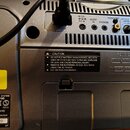 Zadní strana stříbrného audio systému s řadou konektorů a ovládacím prvkem LEVEL. Na zařízení jsou vidět nápisy DC IN, AUDIO IN, PHONES, VIDEO OUT a…