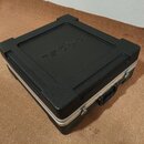 Černý tvrdý kufr s texturovaným povrchem a stříbrnými kovovými hranami. Na víku je vyražen nápis PROEL. Kufr má na boku černou plastovou rukojeť a ko…