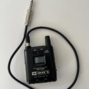 Černý bezdrátový vysílač s připojeným kabelem a 6,3mm jack konektorem. Na zařízení jsou nápisy LINE 6, RELAY, TBP12 TRANSMITTER a 2.4GHz DIGITAL WIRE…
