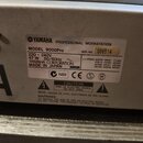 Fotografie detailně zachycuje stříbrný štítek s technickými údaji na povrchu přístroje. Na štítku je uvedeno logo a nápis YAMAHA PROFESSIONAL WORKSTA…