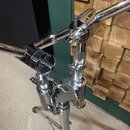 Detailní pohled na chromovaný kovový stojan s několika rameny a utahovacími šrouby. Na středovém kloubu je vyryt nápis "PREMIER". Povrch je lesklý, s…