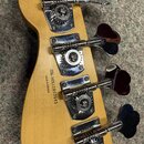 Zadní strana hlavy světle hnědé kytary s čtyřmi chromovanými ladičkami. Na dřevě je černý nápis MADE IN MEXICO a SERIAL NUMBER MX12003593. Povrch dře…