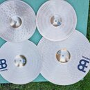 Sada čtyř cymbálů z mosazi v přírodním zlatavém odstínu, položená na zelené podložce. Dva spodní cymbály mají modré logo „B“ a pod ním nápis „MEINL“.…