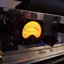 Detailní pohled na přední panel stříbrného zesilovače s nápisy INPUT, INSTRUMENT a INPUT LEVEL. Uprostřed je umístěn žlutý VU metr s nápisy VU, Askdo…
