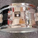 Chromovaný malý buben s kovovým korpusem. Uprostřed je černý štítek s bílým nápisem MAPEX PERCUSSION TECHNOLOGY a pod ním menší text MADE IN TAIWAN R…