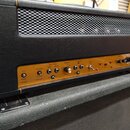 Zadní strana kytarového zesilovače v černém vinylu s kovovou mřížkou. Zlatý ovládací panel obsahuje přepínače a konektory s nápisy SPLIT, SHARED CATH…