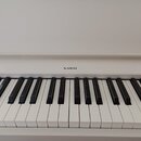 Bílé digitální piano s klávesnicí. Nad klávesami je umístěn nápis KAWAI. Povrch nástroje i kláves vypadá čistě a v dobrém stavu.