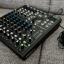 Černý mixážní pult s řadou modrých, žlutých a bílých ovratových knoflíků a posuvníků. Na pravé straně je vidět nápis PROFX, logo PreSonus a označení…