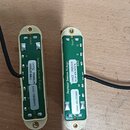 Dvě elektrické snímače s bílými plastovými rámečky a zelenými základními deskami. Na levém snímači jsou nápisy Seymour Duncan Pickups, LATTQ 2020129,…