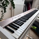 Bílá digitální klaviatura s černými a bílými klávesami. Na levé straně horního panelu je viditelné logo NUX. Horní ovládací panel obsahuje několik tl…