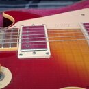 Detail elektrické kytary s červeno-žlutým přechodem barvy (sunburst) a kremovým pickguardem. Na pickguardu je nápis 1960 zrcadlově otočený. Vidět jso…
