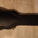Černý tvrdý kufr na kytaru v akustickém tvaru. Na povrchu je zlatým nápisem logo Gibson a pod ním text CUSTOM s hvězdou. Kufr vykazuje mírné opotřebe…