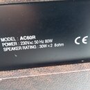 Detailní záběr na černý štítek s bílým textem na zadní straně přístroje. Je zde uveden nápis MODEL : AC60R, POWER : 230VAC 50 Hz 80W a SPEAKER RATING…