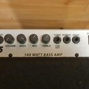 Detail ovládacího panelu basového zesilovače s nápisem LA15 a 100 WATT BASS AMP. Panel obsahuje vstup INPUT, čtyři otočné potenciometry s popisky VOL…