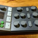 Šedý digitální mixér s názvem MCaster STUDIO a logem výrobce. Zařízení obsahuje displej, zelené ovládací tlačítka a čtyři bílá tlačítka s nápisy S1,…
