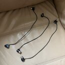 Tři černé audio kabely s konektory na obou koncích. Na některých konektorech jsou vidět modré značky s bílým textem, který je nečitelný. Kabely leží…