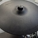 Černý elektronický činel s koncentrickými drážkami na povrchu. V horní části je viditelné logo Roland. Nástroj vykazuje mírné opotřebení a prach na p…