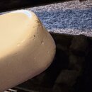 Detailní záběr na bílý, lakovaný roh hudebního nástroje. Povrch vykazuje známky opotřebení v podobě několika drobných odřesů a stínů na hraně. Žádné…