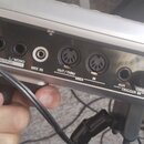 Záběr na zadní panel stříbrného elektronického zařízení. Jsou zde vidět konektory s nápisy USE ROLAND PSB-1U ADAPTOR ONLY, DC IN, OUTPUT (R a L/MONO)…