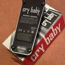 Fotografie zachycuje spodní stranu efekt pedálu v černé barvě s kovovým tělem. Na povrchu jsou nápisy „cry baby“, „MODEL GCB95“ a logo „Dunlop“. Je z…