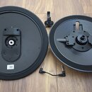 Dvě černé kulaté desky z plastu a kovu, pravděpodobně části elektronického bicího soupravu. Na obou deskách je viditelný nápis LINK. K deskám patří č…