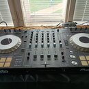 Šedý DJ controller s dvěma velkými stříbrnými jogovými koly a ovládacími prvky v centrech. Na přístroji jsou viditelné nápisy serato, PROFESSIONAL DJ…