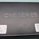 Černý kartonový box s nápisem ONE SERIES. Na levé straně je bílá nálepka s textem: Importer: Warwick GmbH & Co Music Equipment KG Gewerbepark 46 DE-0…