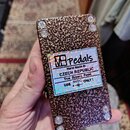Zadní strana efekt pedálu s hnědým, strukturovaným kovovým povrchem. Uprostřed je nalepená holografická nálepka s nápisy „MB Pedals“, „Hand Made in C…