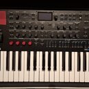 Černý klávesový syntetizátor s bílými klávesami. Na levé straně je logo KORG a na pravé nápis modwave mkII WAVE TABLE SYNTHESIZER. Horní panel obsahu…