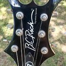 Černá hlava elektrické kytary s výrazným, špičatým tvarem. Na povrchu je bílý nápis B.C. Rich a menší text Signature Special TM. V dolní části hlavy…