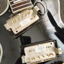 Fotografie zachycuje dvě humbuckery v černé elektrické kytáře. Horní snímač má na spodní straně bílou nálečku s nápisem „490 R abs-30902-L 01/18/19“.…