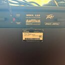Zadní strana černého basového komba s logem Peavey. Na horním štítku je nápis MINX. 110 BASS AMPLIFICATION SYSTEM a varovné texty v angličtině. Spodn…
