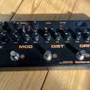 Černý kytarový efekt pedál s nápisy DELAY, MOD, DIST a DRIVE. Na spodní pravé straně je uveden název modelu Cerberus a značka NUX, dále nápisy TRUE B…