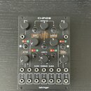 Černý modul s nápisem CHAOS v horní části a behringer ve spodní. Zařízení obsahuje několik otočných potenciometrů, tlačítka a v dolní části 12 zapušt…