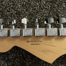 Detail zadní strany hlavy kytary z přírodního dřeva s chromovanými ladičkami. Na dřevě je černý nápis SERIAL NUMBER MX18018568 a pod ním MADE IN MEXI…