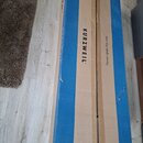 Dvě dlouhé cardboardové krabice hnědé barvy s modrými pruhy. Na levé krabici je černý nápis KURZWEIL®. Na pravé krabici je svislý černý nápis Please…