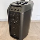 Černý reproduktor s ovládacími prvky na zadní straně. Jsou zde viditelné nápisy VOLUME TREBLE BASS REVERB, vstupy INPUT 1 a 2, AUX a výstup LOW OUT.…