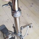 Stříbrný kovový stativ s teleskopickou nohou a utahovacím šroubem. Na středovém článku je viditelný nápis: "Do not tighten too much. Do not use tube…