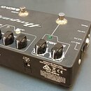 Černý DI box s nápisy Ampeg a SCR-DI. Na horní ploše jsou čtyři ovládací knoflíky, dva přepínače a dva zapínací tlačítka. Na boku je vidět logo Ampeg…