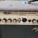 Detail horní části akustického komba s hnědým texturovaným povrchem. Na ovládacím panelu je nápis MEGATONE ACOUSTIC AMPLIFIER a označení sekcí CHANNE…
