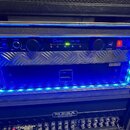 Černý rackový case s modrým LED podsvícením, v němž je osazen přístroj značky the tracks s označením VM-100. Přístroj má dvě černé otočné voliče, čer…