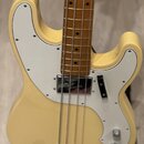 Světle žlutá elektrická basová kytara s bílým pickguardem a hnedým hmatníkem. Na snímači je viditelný nápis "Precision Bass". Nástroj vykazuje minimá…
