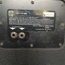 Fotografie zachycuje zadní štítku basové reproboxy značky ampeg. Na štítku je uveden model SVT-212E a sériové číslo 32ED60043. Je zde uveden nápis ma…