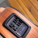 Detailní záběr na předzesilovač s ekvalizérem vestavěný do dřevěného korpusu akustického nástroje. Černý ovládací panel obsahuje pět posuvníků, dva p…
