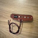 Humbucker snímač s červeným plastovým krytem a šesti kovovými póly. Na černé nálepce je bílý nápis TG N. Ze spodní strany vedou dva červeně-černé vod…