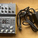 Žlutý mixážní pult s šedým předním panelem a nápisem TAPCO MIX50. Zařízení obsahuje různé vstupy, potenciometry a přepínače, z nichž jsou čitelné pop…
