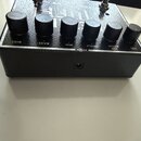 Černý efekt pedál s texturovaným povrchem. Na horní straně se nachází šest černých otočných oválů s popisky DIST, BASS, MID, TREBLE, TOP BOOST a VOL.…
