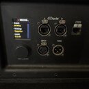 Detail zadní strany černého reproduktoru s ovládacím panelem. Je zde digitální displej s nápisy „RSX208...“, „Input: Analog“, „Voicing: Sapphire“ a „…