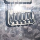 Detailní záběr na černý kovový kobylník elektrické kytary s pružinami. V horní části je vidět část černého snímače s nápisem Seymour Duncan. Tělo kyt…