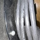 Detailní záběr na černý napájecí kabel svlnutý kolem černého kovového povrchu. Na izolaci kabelu je bílý nápis: ce UKCA C4F42 0.75mm² AWG23/7. Povrch…